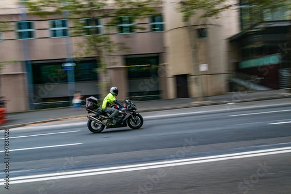 Obraz A motorcycle moving on the road, Sydney, Australia. A motorcycle in motion on the road, blurred building in background.