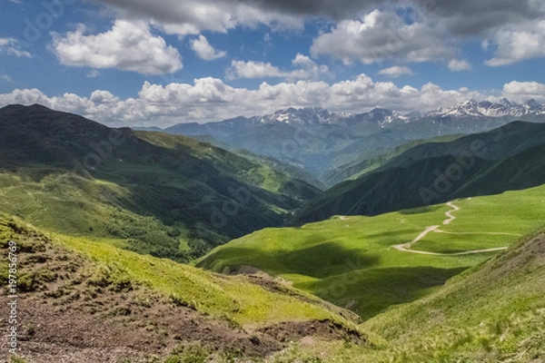 Fototapeta Scenic view of Hevsureti, Georgia. Caucasus mountains on the background, green valley on the foregound. Hot summer day. Concept of clear ecosystem.