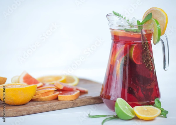 Fototapeta tasty and juicy sangria with citrus in a glass next to the pitcher on a white background...