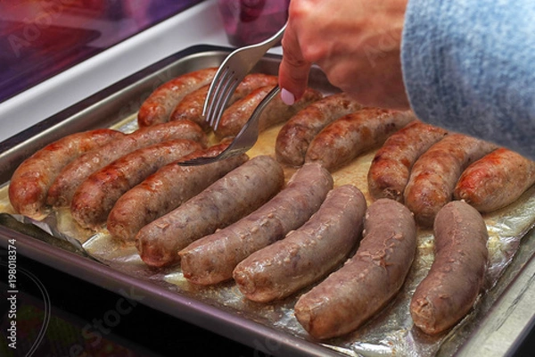 Fototapeta Homemade sausages are roasted on a protvin in their own fat