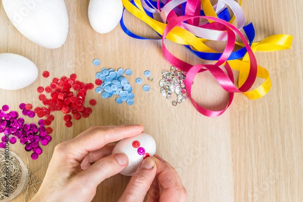 Fototapeta Hand holding easter polystyrene egg decorating pink sequins