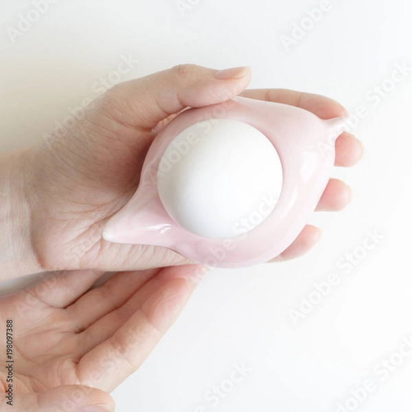 Obraz Woman's hands holding egg stand with white egg. Top view. Easter Composition