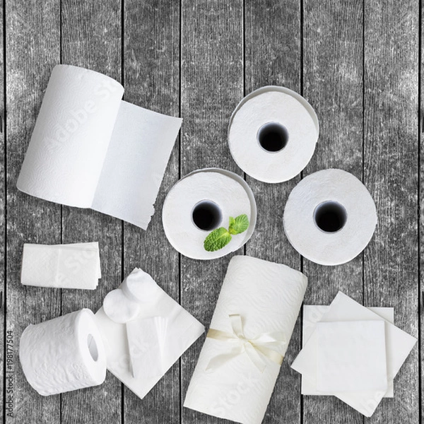 Fototapeta Paper tissue, white toilet  paper rolls, towels, napkins, cotton pads stacked on rustic wooden table. Copy space.