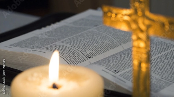 Obraz open Bible next to a lit candle and cross with the crucified Jesus Christ