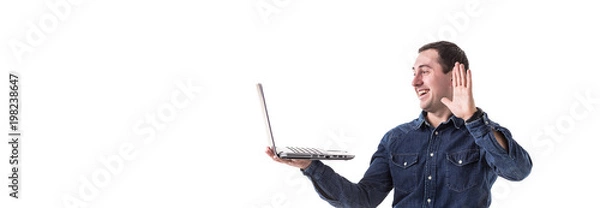 Fototapeta young programmer (man) holding a laptop in hands and talking on skype with friends isolated on white background. Copy space