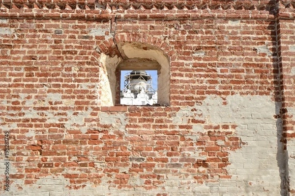 Fototapeta Окно в кирпичной стене сквозь которое видно церковь
