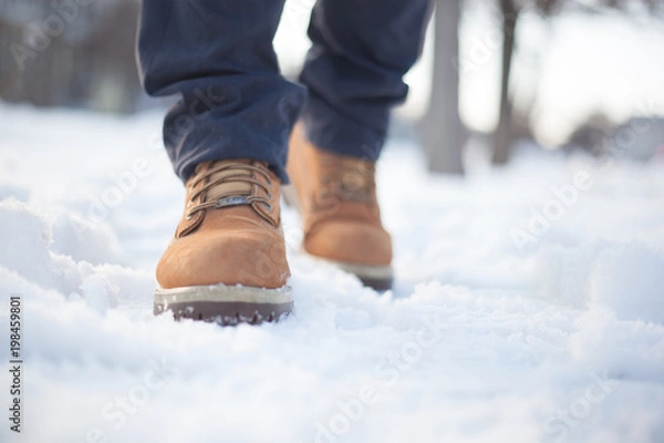 Obraz A man in red shoes and gray jeans is walking on the snow