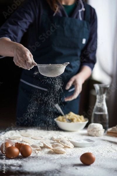 Fototapeta Image of hard working male cook or baker with dark skin wears apron, sheets well made dough, going to bake tart, isolated over black chalk background. Unrecognizable African American chef on kitchen