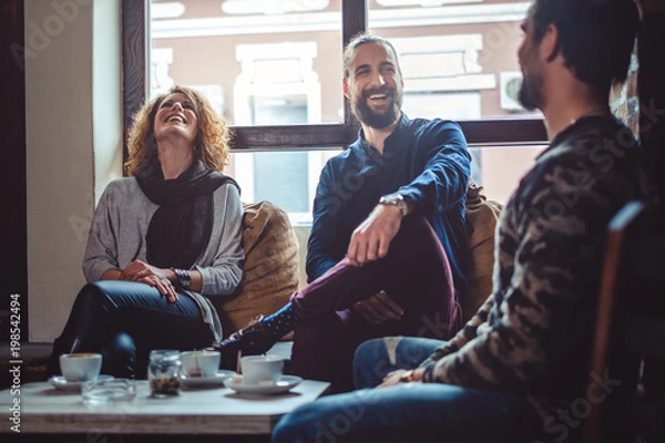 Obraz Friends laughing in a cafe while drinking coffee