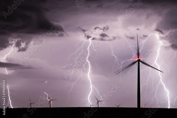 Fototapeta Thunderstorm with lightnings over a wind farm
