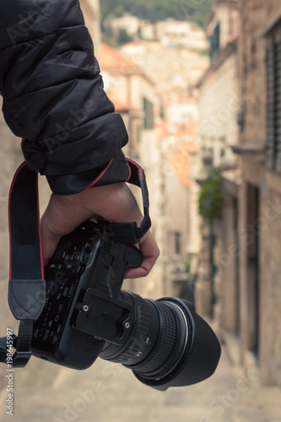 Fototapeta Male photographer holding digital camera while travelling through Europe. Portrait image.