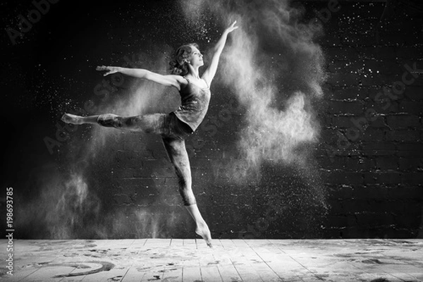 Fototapeta beautiful ballet dancer dancing barefoot on black background in a cloud of dust