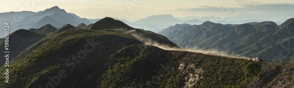 Fototapeta panorama of our Mitsubishi pick-up driving over the crest of beautiful green hills followed by a dust cloud trail at Torotoro National Park