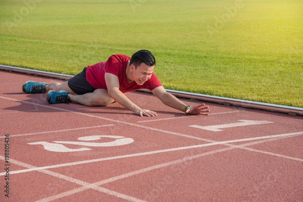 Obraz Sad asian runner sitting on the ground after losing in competition