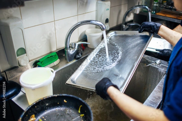 Obraz cook washes the tray with running water