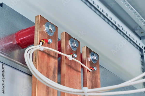 Fototapeta Electrical wires are connected to copper busbars. Busbars are fixed to the circuit Board through red insulators. Electrical equipment is installed in the enclosure of the electrical Cabinet.