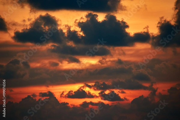 Obraz Sunset Clouds. Dramatic sunset in orange sunlight. Flaming sunset with light passing through the dark clouds. Landscape.