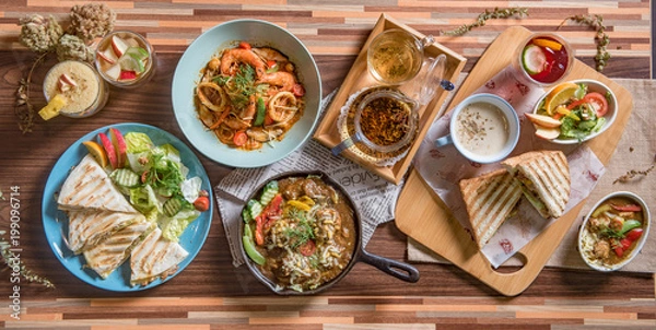 Obraz Widok z góry na kreatywne zdjęcie przyjaciół siedzących przy rustykalnym drewnianym stole.