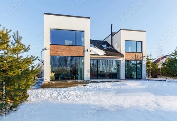 Obraz Nowoczesny dom z dużymi panoramicznymi oknami w tle pokrytego śniegiem krajobrazu
