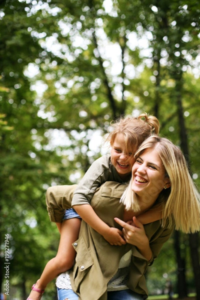 Obraz Little girl on a piggy back ride with her mother.