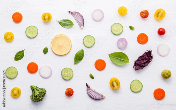 Fototapeta Food pattern with raw ingredients of salad. Various vegetables lettuce leaves, cucumbers, tomatoes, carrots, broccoli, onion and lemon flat lay on white background.