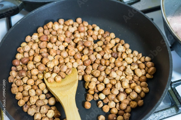 Fototapeta fry hazelnuts in a frying pan. fresh nuts in the pan.