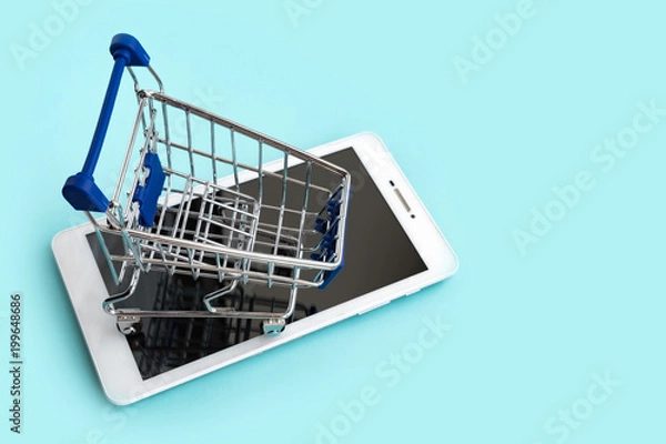 Obraz Tablet computer and small cart for shopping on cyan background. Internet shopping concept. copy space.