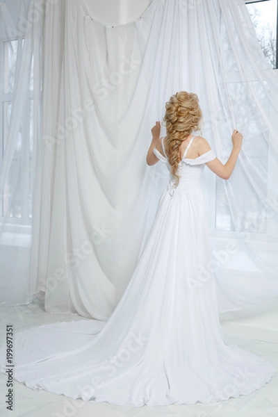 Fototapeta Невеста стоит у окна в белом платье