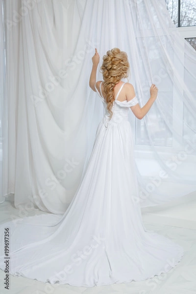 Fototapeta Невеста стоит у окна в белом платье