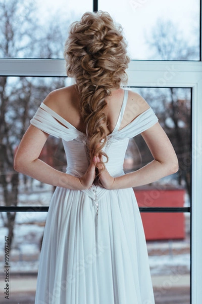 Fototapeta Невеста стоит у окна в белом платье