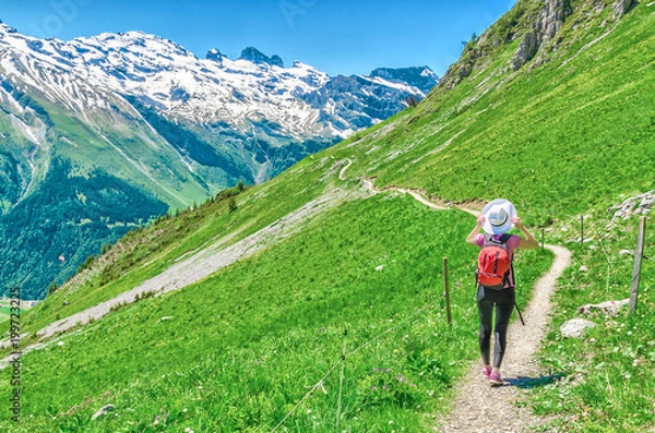Fototapeta Swiss Alps. A man in a white hat, a traveler in a mountain alpine country walk along the path. Landscape of the Swiss Alps, Engelberg Resort