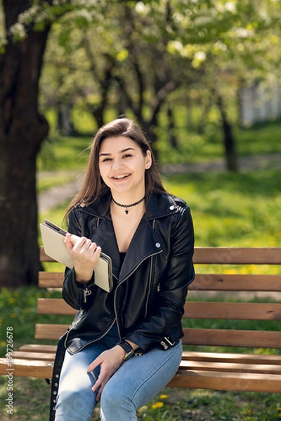 Fototapeta Beautiful caucasian girl student sitting on bench in park reading book