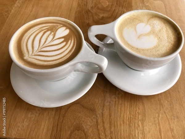 Obraz Two romantic cups of chocolate mocha or caramel latte with  beautiful design in a cups of coffee  on a table in fancy  cafe in Portland Oregon USA
