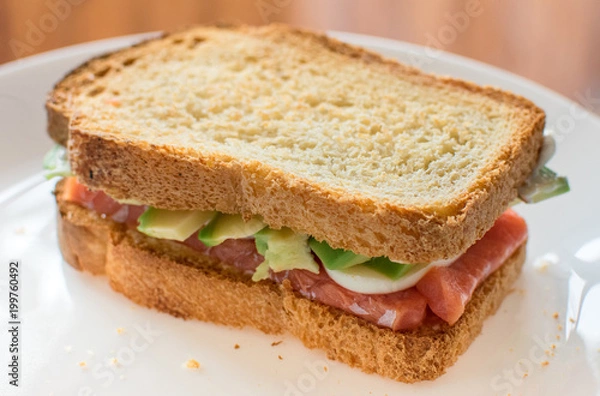 Fototapeta healthy Breakfast: toast with avocado, salmon and egg on wholemeal bread. Mediterranean diet, healthy food.