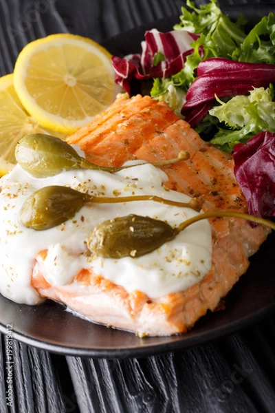 Fototapeta Salmon piccata with fresh mix salad closeup. vertical
