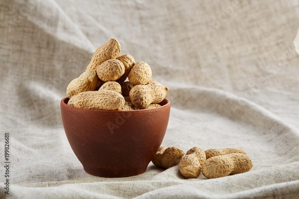 Fototapeta Salted pistachios on a wooden plate over white background, top view, close-up, selective focus.