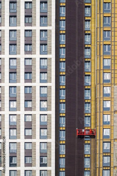 Fototapeta Worker at height in a red construction cradle