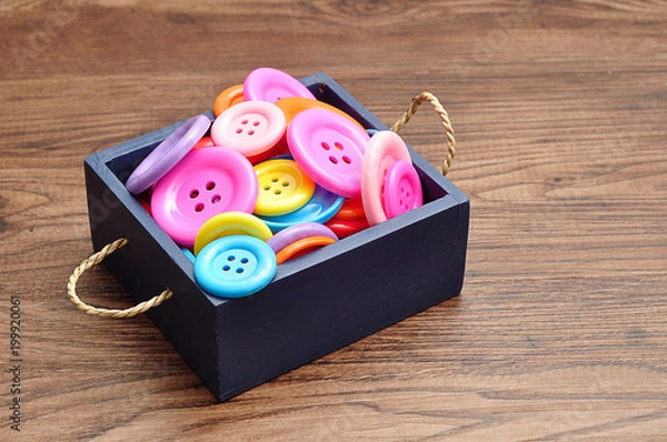 Obraz A blue bucket filled with colorful buttons in different sizes