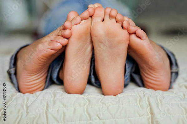 Obraz Beautiful funny feet of  young children lying in bed close up