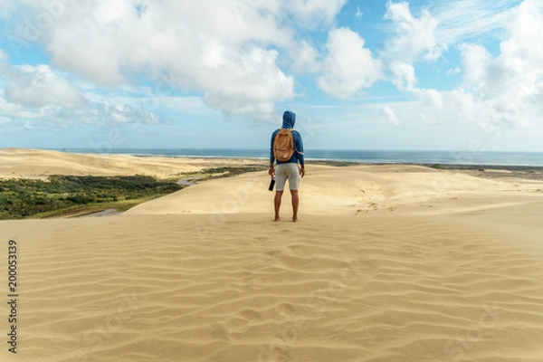 Fototapeta rear view of lonely hiker standing on sand dune and looking away, Giant Sand Dunes, New Zealand