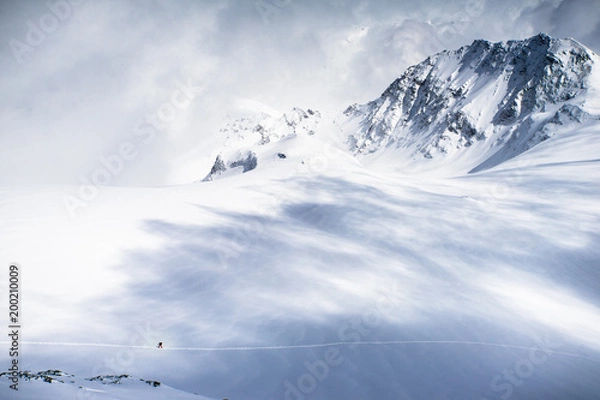 Fototapeta A lone skier exploring the snow fields and high mountains of the Swiss Alps