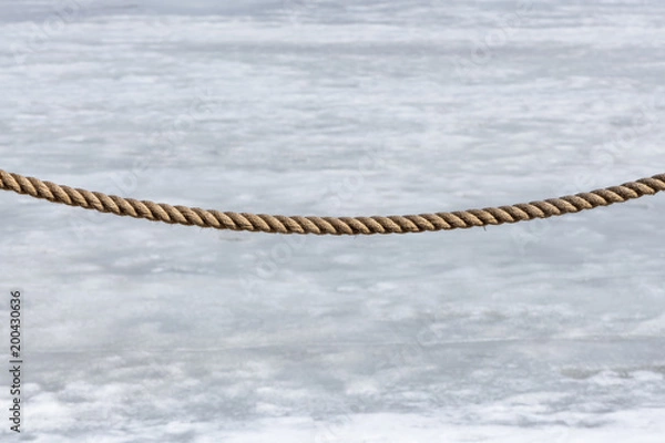Obraz Fence rope on a snow-melting background.