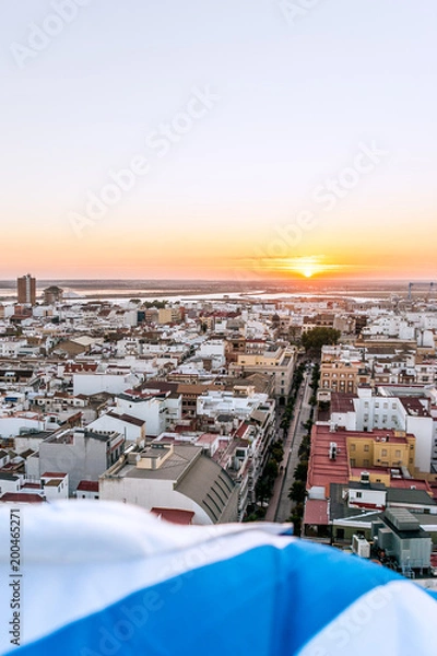 Fototapeta Aerial view of the sunset in Huelva, with the white and blue flag of the 