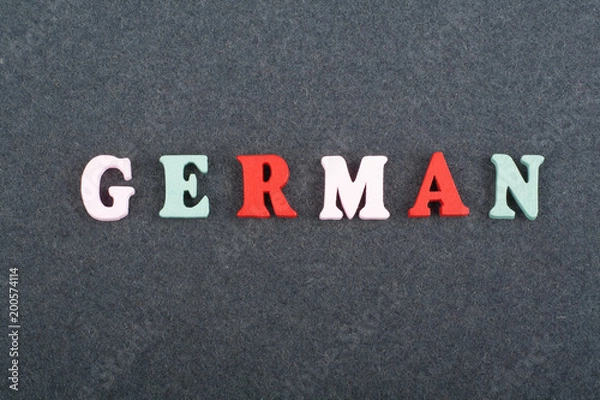 Fototapeta German word on black board background composed from colorful abc alphabet block wooden letters, copy space for ad text. Learning english concept.