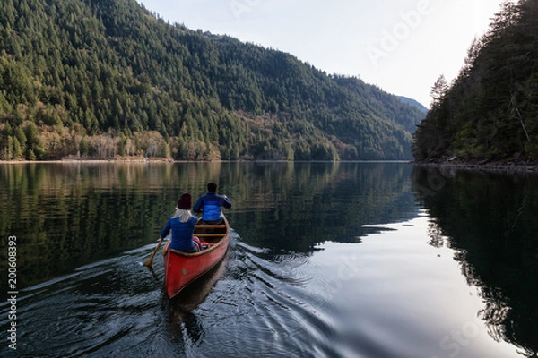 Fototapeta Couple friends canoeing on a wooden canoe during a sunny day. Taken in Harrison River, East of Vancouver, British Columbia, Canada.
