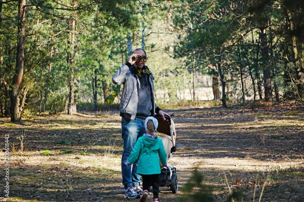 Fototapeta Dad and daughter watch the birds through binoculars. Birdwatchers in the spring forest.