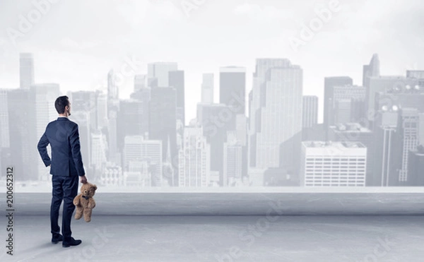 Fototapeta Businessman standing with his back on a roof with objects in his hand
