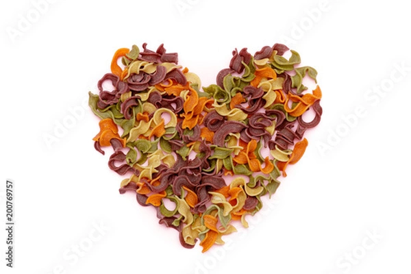 Fototapeta Dried pasta in heart shape top view. Colorful vegetable pastas on isolated background