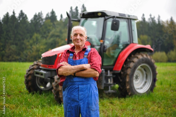 Fototapeta Proud farmer standing in front of his red tractor