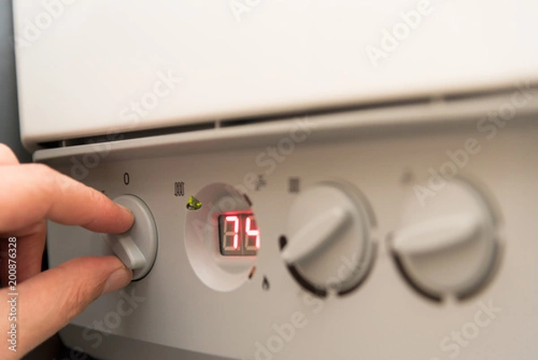 Fototapeta Fingers of a adult man turning on a British Combi Gas Boiler